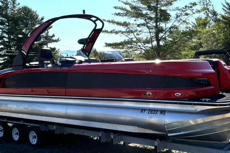  Yacht Photos Pics 2022 Manitou XT 27 SRW pontoon boat in vibrant red, parked on a trailer.