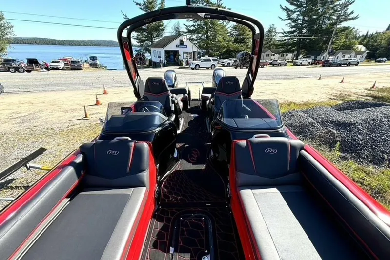  Yacht Photos Pics 2022 Manitou XT 27 SRW pontoon boat interior with red and black seating, near a lakeside.
