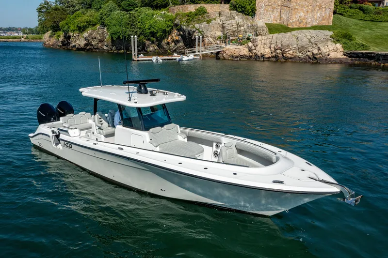  Yacht Photos Pics 2024 HCB 39 Speciale luxury boat on calm water near rocky shoreline.