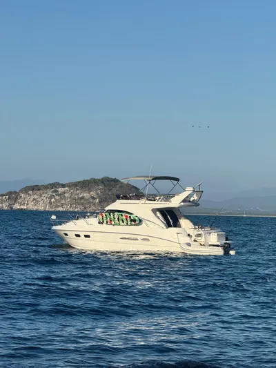  Yacht Photos Pics 2009 Sealine F42/5 yacht cruising on calm sea near rocky island.
