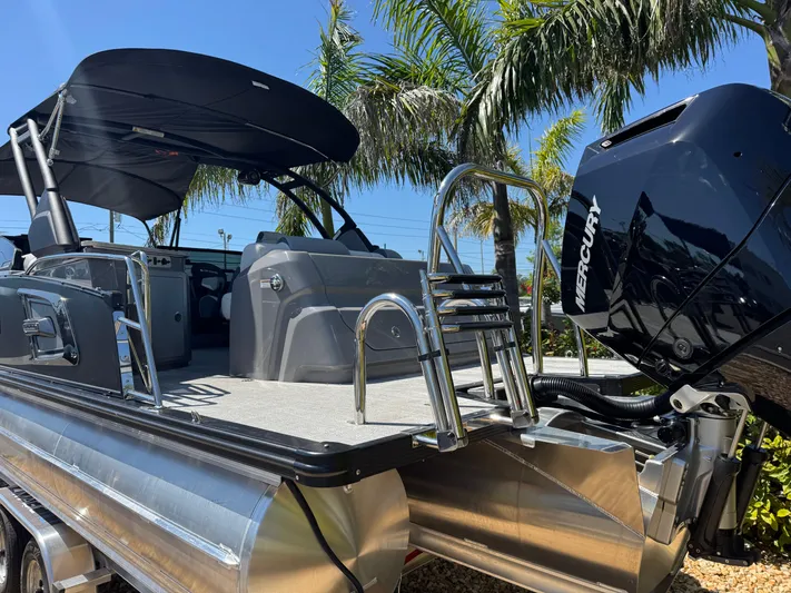  Yacht Photos Pics 2025 Avalon Excalibur 27' boat with Mercury engine, sleek design, palm trees in background.