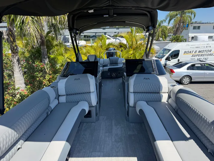  Yacht Photos Pics 2025 Avalon Excalibur 27' boat interior with luxurious seating and canopy, surrounded by palm trees.
