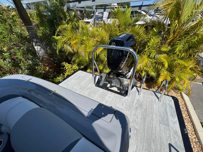  Yacht Photos Pics 2025 Avalon Excalibur 27' boat with sleek seating and powerful outboard motor, surrounded by lush greenery.