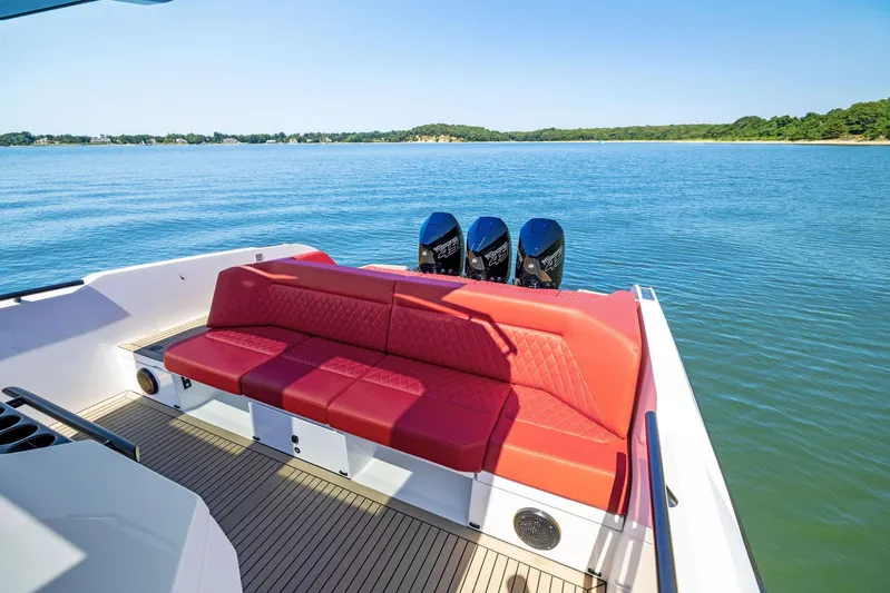 Outrageous Yacht Photos Pics 2024 Vanquish Yachts VQ 40 with red seating and triple outboard engines on a serene lake.
