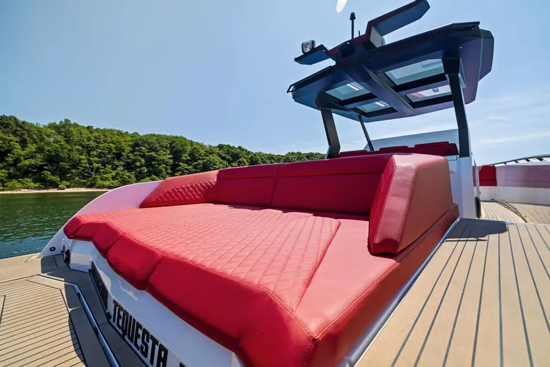 Outrageous Yacht Photos Pics 2024 Vanquish Yachts VQ 40 with red seating on deck, docked near lush greenery.