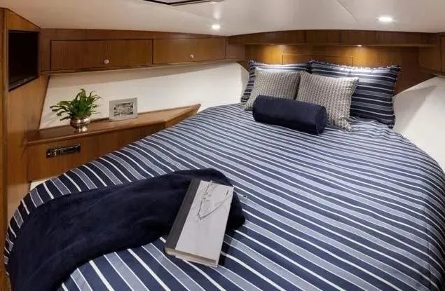 Yacht Photos Pics Luxurious cabin interior of 2013 Cabo 40 Hardtop Express with striped bedding and cozy decor.