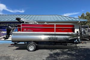 2026 Sun Tracker Party Barge 18 DLX pontoon boat with red exterior on trailer.