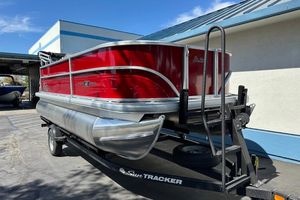 2026 Sun Tracker Party Barge 18 DLX pontoon boat on trailer, vibrant red exterior.