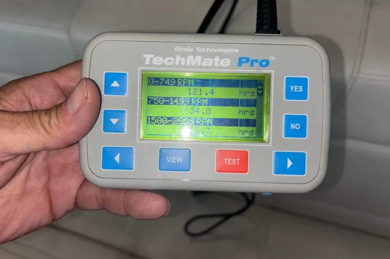  Yacht Photos Pics Hand holding TechMate Pro diagnostic tool displaying RPM hours for Fountain 42 Executioner boat.