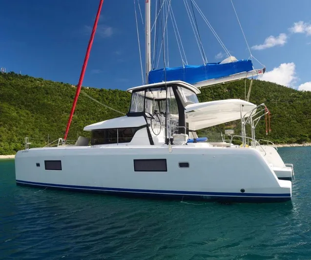 Pau Hana Yacht Photos Pics 2020 Lagoon 42 catamaran anchored in clear blue water, with lush green hills in the background.