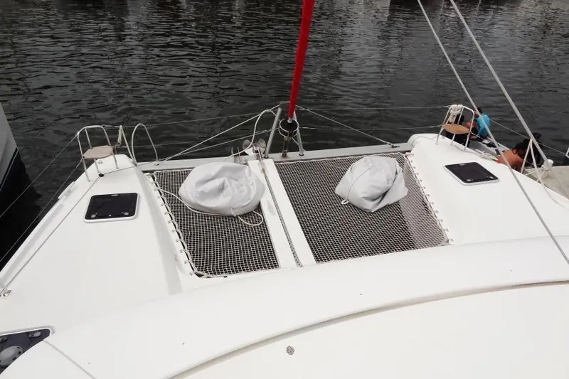 Pau Hana Yacht Photos Pics Catamaran Lagoon 42 (2020) with netted deck, docked on calm water.