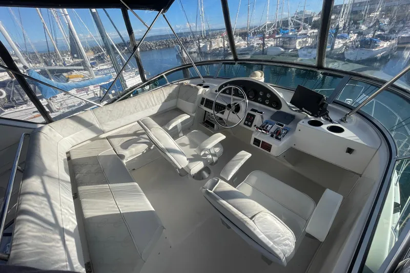 Happy Phantom Yacht Photos Pics 1996 Bayliner 4087 Aft Cabin Motoryacht helm with marina view, featuring white seating and controls.