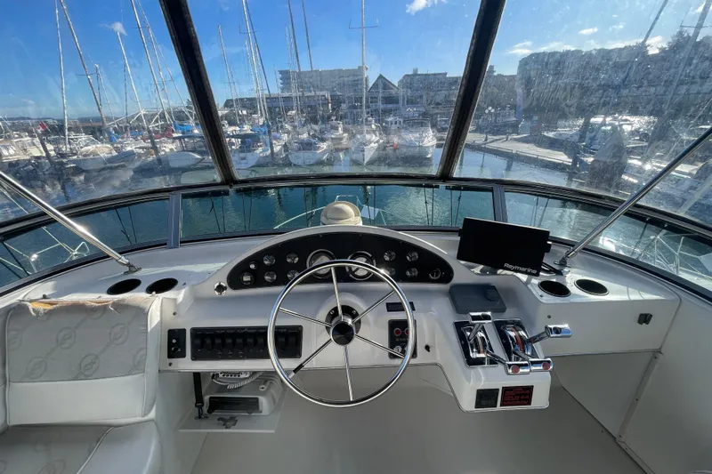 Happy Phantom Yacht Photos Pics 1996 Bayliner 4087 Aft Cabin Motoryacht helm with marina view, featuring steering wheel and controls.