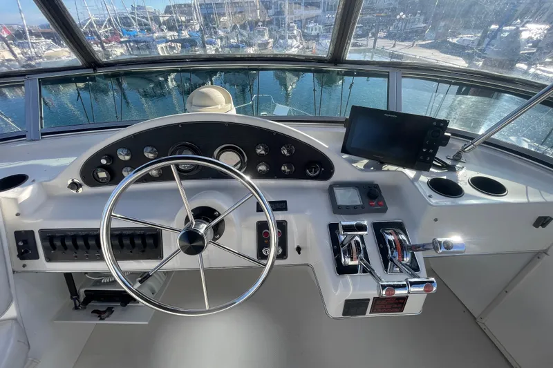 Happy Phantom Yacht Photos Pics 1996 Bayliner 4087 Aft Cabin Motoryacht helm with steering wheel and navigation controls.