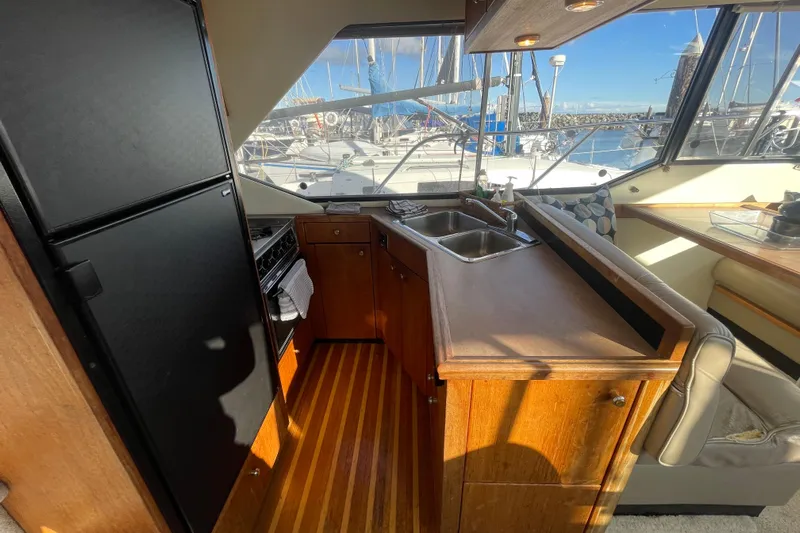 Happy Phantom Yacht Photos Pics 1996 Bayliner 4087 Aft Cabin Motoryacht interior with kitchen, sink, and seating area.