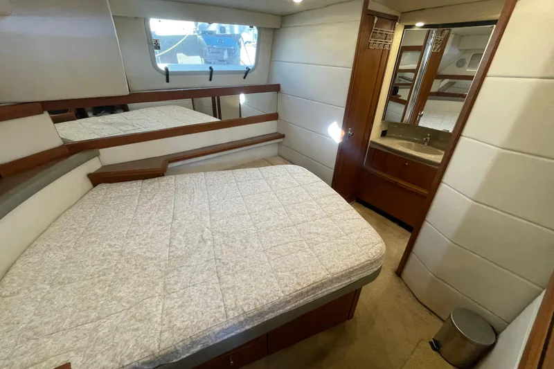 Happy Phantom Yacht Photos Pics 1996 Bayliner 4087 Aft Cabin Motoryacht bedroom with bed, mirror, and sink area.