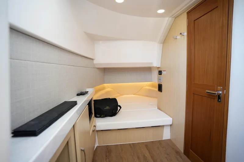  Yacht Photos Pics 2024 Regal 38 SAV interior cabin with seating, wooden door, and modern lighting.