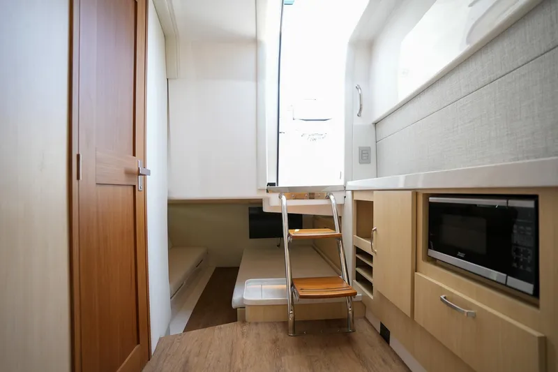  Yacht Photos Pics 2024 Regal 38 SAV interior with wooden cabinetry, compact kitchen, and cozy sleeping area.
