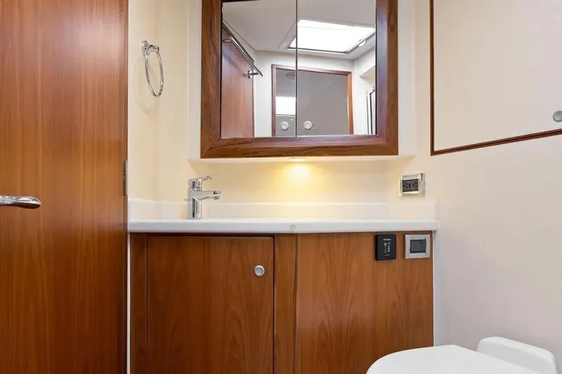  Yacht Photos Pics 2012 Cabo 44 Hardtop Express yacht bathroom with wooden cabinetry and mirrored cabinet.