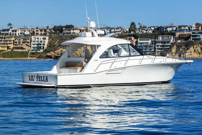  Yacht Photos Pics 2012 Cabo 44 Hardtop Express yacht on calm water near coastal homes.