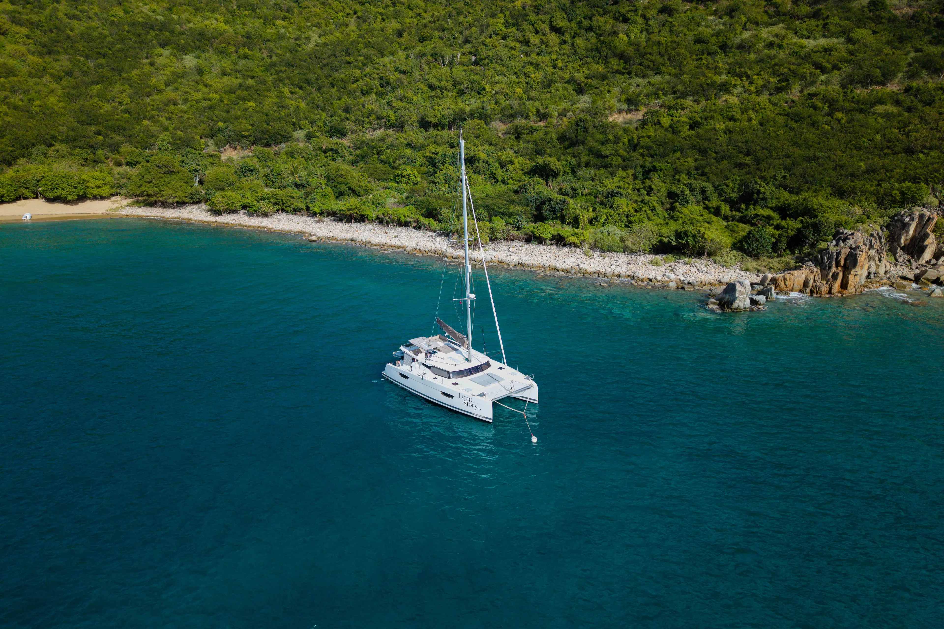 Long Story Yacht Photos Pics 2019 Fountaine Pajot Saona 47 catamaran anchored near lush green coastline.