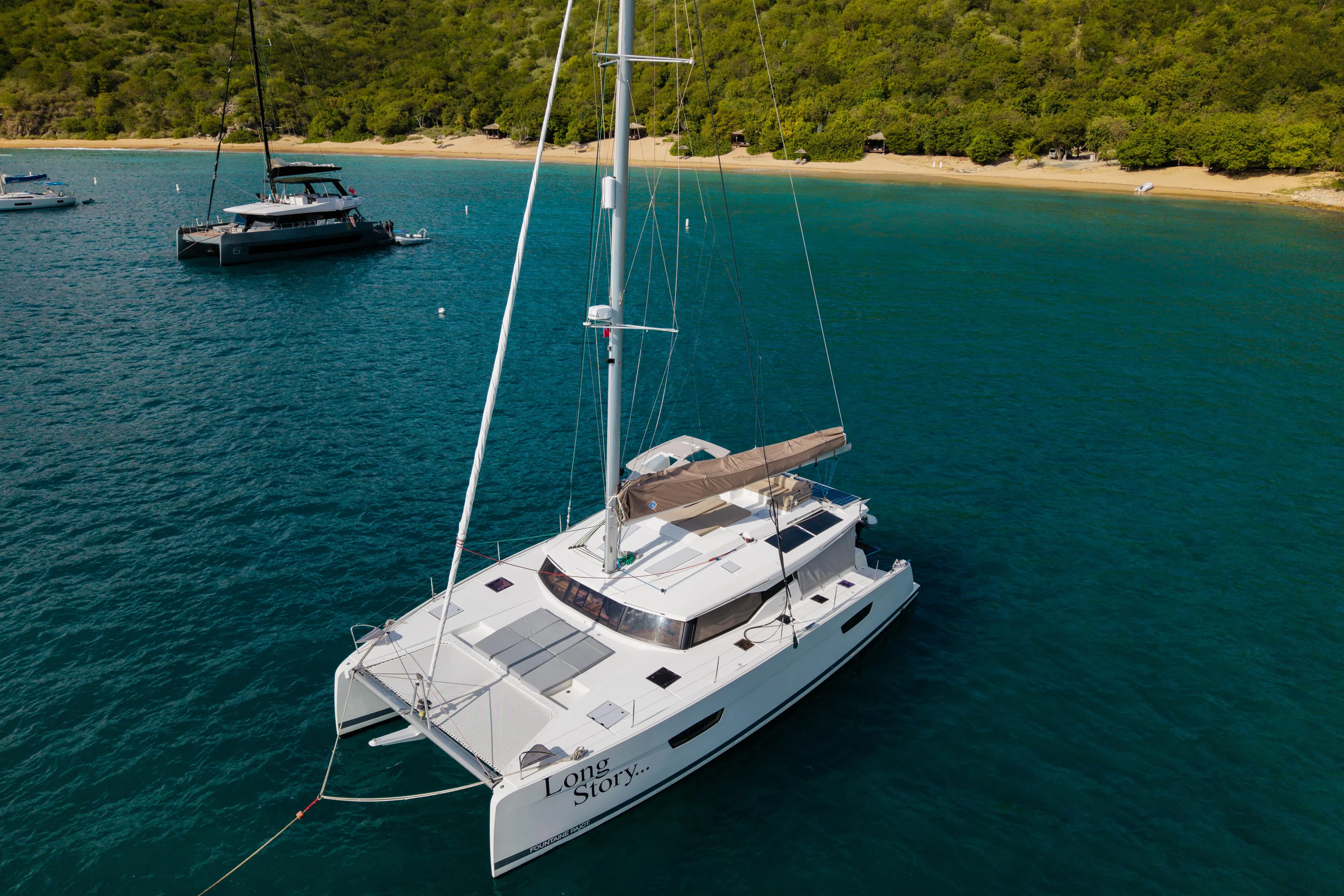 Long Story Yacht Photos Pics 2019 Fountaine Pajot Saona 47 catamaran anchored near a tropical beach.