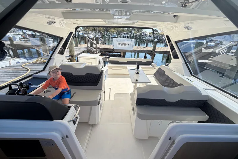 Chasin' Hyde Yacht Photos Pics 2023 Aquila 36 Sport interior with seating and a child at the helm.