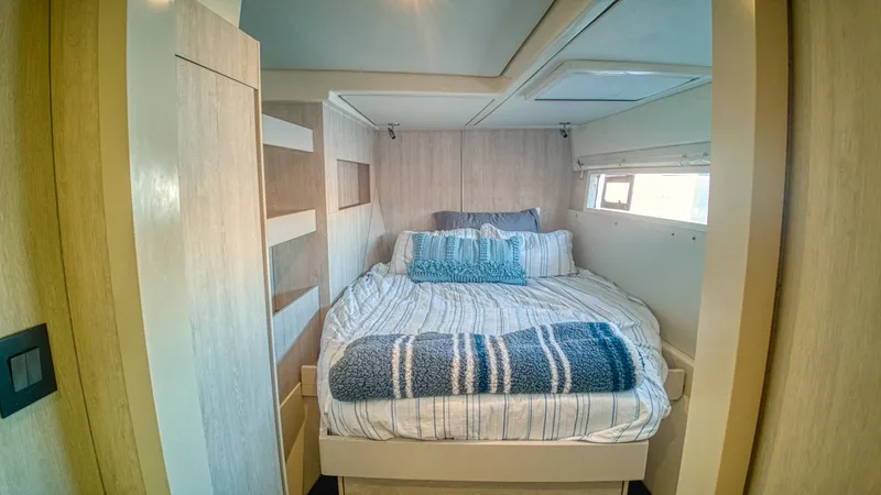 Jubilee Yacht Photos Pics Cozy bedroom interior in a 2015 Leopard 48 yacht with striped bedding and natural light.