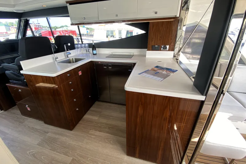  Yacht Photos Pics Luxurious kitchen interior of 2025 Riviera 465 SUV yacht with modern wood cabinetry.
