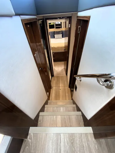 Yacht Photos Pics Interior staircase of 2025 Riviera 465 SUV yacht, leading to a cozy cabin.