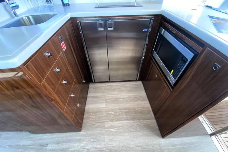  Yacht Photos Pics Modern kitchen in 2025 Riviera 465 SUV yacht with wood cabinetry and stainless steel appliances.