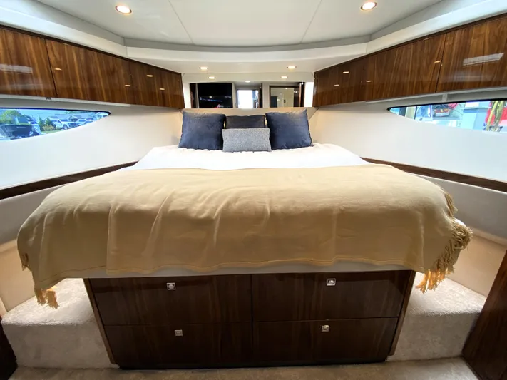  Yacht Photos Pics Luxurious bedroom interior of 2025 Riviera 465 SUV yacht with elegant wood finishes.