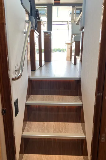  Yacht Photos Pics Staircase inside 2025 Riviera 465 SUV yacht, featuring sleek wooden design.