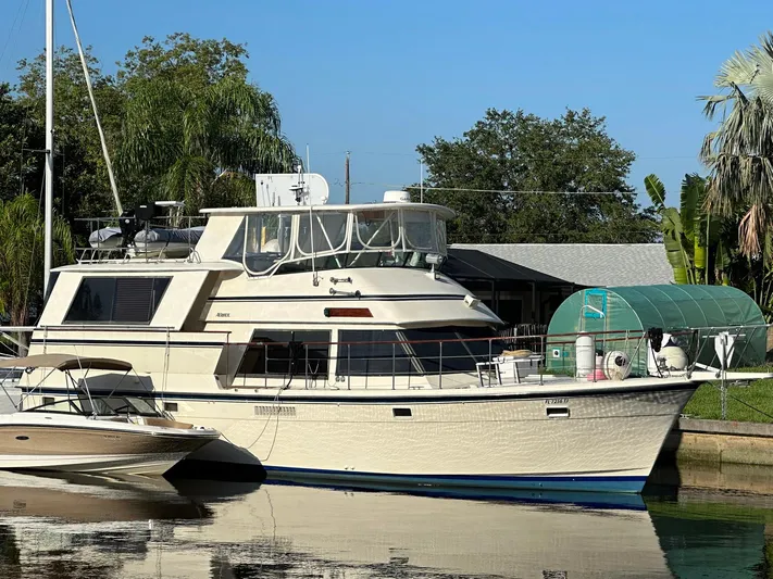 Luv'n Life Yacht Photos Pics 1989 Atlantic 47 Motor Yacht docked near lush greenery and a smaller boat.