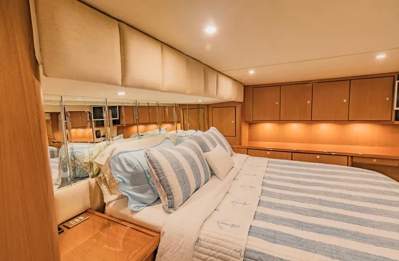  Yacht Photos Pics Luxurious bedroom interior of 1999 Ocean Yachts 60 Convertible with striped bedding and wood cabinetry.