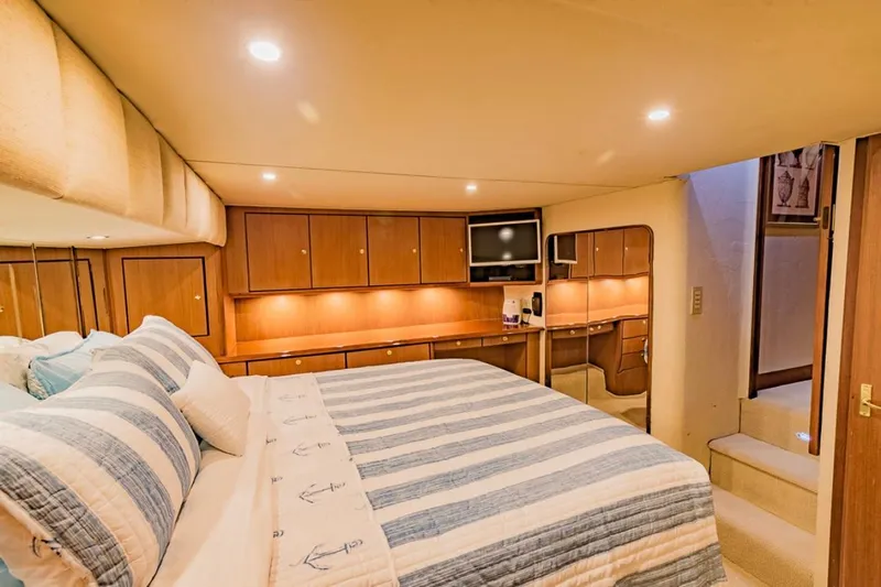  Yacht Photos Pics Luxurious bedroom interior of 1999 Ocean Yachts 60 Convertible with striped bedding and wood cabinetry.
