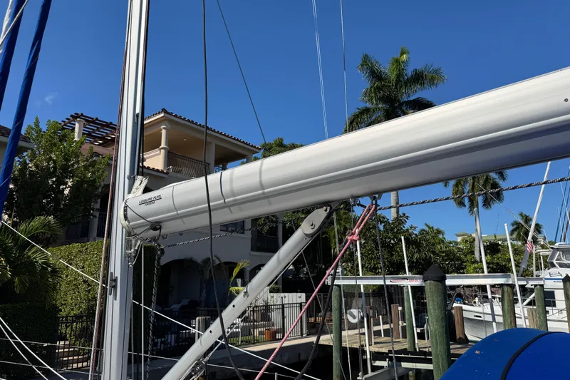 Take 2 Yacht Photos Pics 2019 Beneteau Oceanis 41.1 sailboat mast and boom, docked near tropical waterfront homes.
