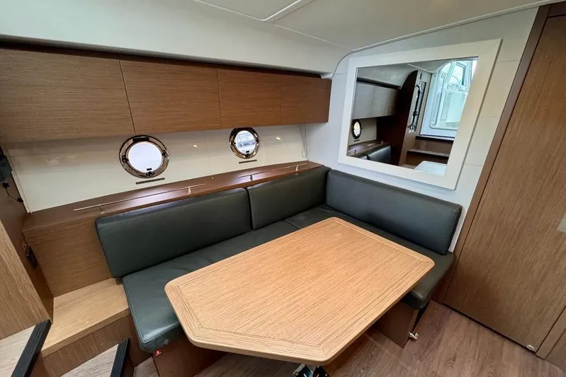  Yacht Photos Pics 2021 Beneteau Gran Turismo 40 interior with dining area, wooden table, and porthole windows.
