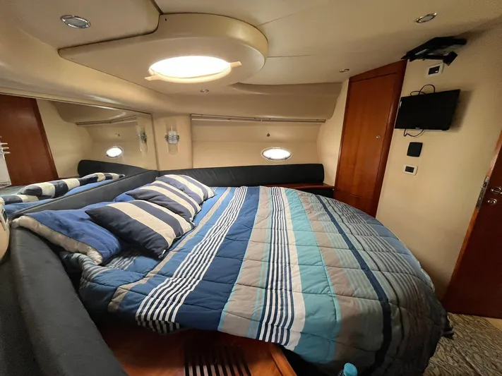  Yacht Photos Pics Luxurious bedroom interior of 2005 Azimut 43 yacht with striped bedding and modern amenities.