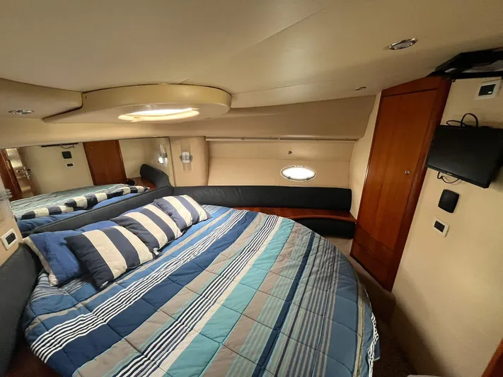  Yacht Photos Pics Luxurious bedroom interior of a 2005 Azimut 43 yacht with striped bedding and modern amenities.
