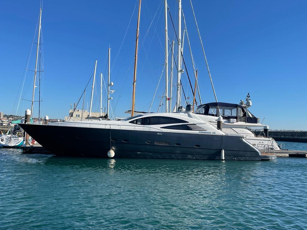 Luxury Pershing 76 yacht from 2004 docked in a marina under clear blue skies.