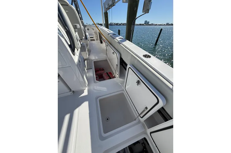  Yacht Photos Pics 2022 Invincible 40 Catamaran deck with open storage compartments, docked by the water.