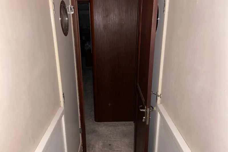  Yacht Photos Pics Narrow hallway inside 1985 Hatteras 53 Extended Deckhouse Motor Yacht, featuring wooden doors and porthole.