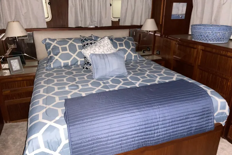  Yacht Photos Pics Bedroom interior of 1985 Hatteras 53 Motor Yacht with geometric bedding and wooden cabinetry.