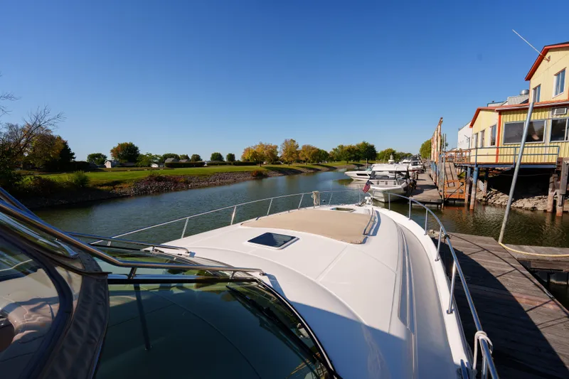  Yacht Photos Pics 2004 Sea Ray Sundancer 460 docked by a scenic riverside under clear blue skies.