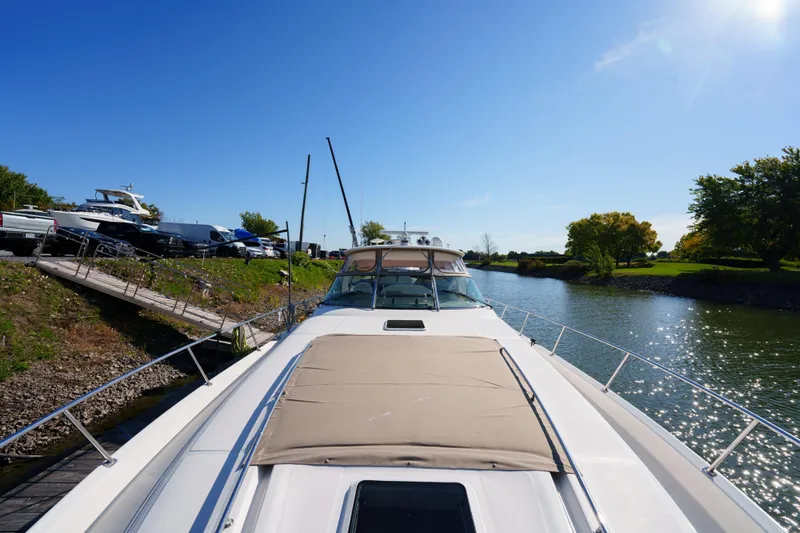  Yacht Photos Pics 2004 Sea Ray Sundancer 460 yacht docked by a scenic river under clear blue skies.