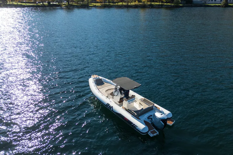  Yacht Photos Pics 2026 BWA GTO 308 boat cruising on a sunlit lake with scenic shoreline.