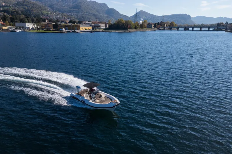  Yacht Photos Pics A 2026 BWA GTO 308 boat cruising on a scenic lake with mountains in the background.