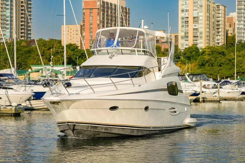  Yacht Photos Pics 2003 Silverton 410 Sport Bridge yacht cruising in a marina with cityscape background.
