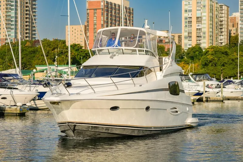  Yacht Photos Pics 2003 Silverton 410 Sport Bridge yacht cruising in a marina with cityscape background.